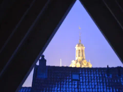 Abendblick durch das dreieckige Dachfenster auf den beleuchteten Drommedaris