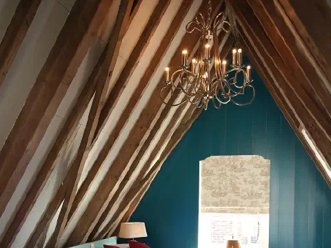Dachzimmer mit Bett unter den Holzbalken